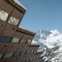 Bâtiment en bois typique des Arcs avec vue sur des sommets enneigés sous un ciel bleu