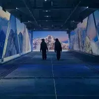Deux personnes marchant dans un tunnel immersif avec projections de sommets enneigés et paysages de montagne à l’Aiguille Rouge