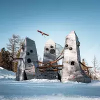 Intérieur d'une cabane géante montrant l'assemblage de poutres en bois brut et un filet de repos en forme de nid suspendu