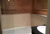 Salle de bain avec baignoire et habillage en bois dans un appartement aux Arcs
