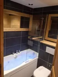 Salle de bains en bois et carrelage noir avec baignoire