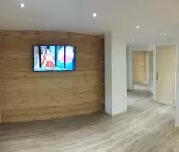 Salon rénové avec mur en bois et télévision