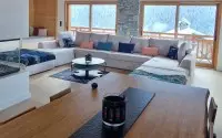 Salon lumineux de chalet avec canapé d'angle et cheminée