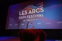 Trophée éclairé de rouge devant le grand écran des Arcs Film Festival 2025.