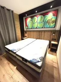 Chambre avec lit double, tête de lit en bois et fresque colorée