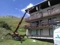 Grue intervenant devant un chalet en montagne