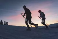 Deux participants du Les Arcs Star Trail courant dans la neige au coucher du soleil