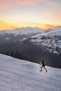 Coureurs du Les Arcs Star Trail sur un parcours enneigé face aux montagnes au coucher du soleil