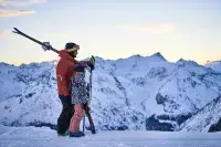 A parent and child skiing at sunrise during First Tracks in Les Arcs