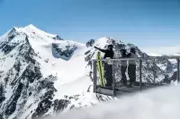 Groupe de skieurs sur une plateforme face aux montagnes alpines.