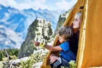 Deux enfants dans une tente face aux montagnes alpines.