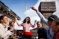 Groupe partageant une fondue sur une terrasse en montagne.