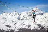 Femme pratiquant la highline face aux montagnes enneigées.
