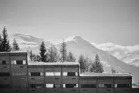 Bâtiments en bois face à des sommets enneigés dans une station de montagne.