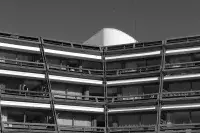Détail architectural d’une façade courbe avec balcons et larges baies vitrées.