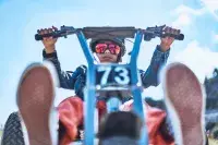 Enfant sur un mountaincart en descente en montagne.