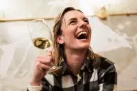 Femme riant avec un verre de vin en ambiance après-ski.