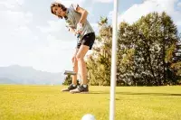 Jeune joueuse réalisant un putt sur un parcours de golf.