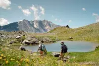 Randonneurs autour d’un lac de montagne fleuri.