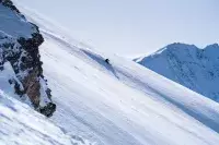 Skieur en hors-piste descendant une pente enneigée en montagne