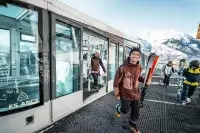 Skieurs sortant du funiculaire en station avec skis à la main