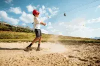 Jeune golfeur frappant une balle depuis un bunker.