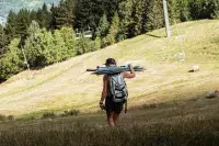 Personne transportant du matériel sur une prairie alpine.