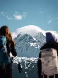 Deux randonneurs en raquettes observant un sommet enneigé sous un ciel dégagé