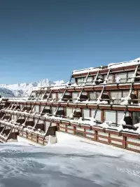 Résidence de montagne aux Arcs avec architecture en terrasses et neige sur les balcons face aux sommets alpins