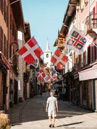 Rue commerçante décorée de drapeaux savoyards dans un village de montagne.