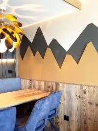 Coin repas avec banquette en bois et décor mural montagne