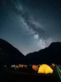 Tentes de bivouac sous un ciel étoilé et la Voie lactée en montagne.