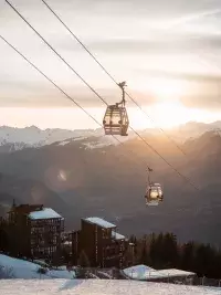 Télécabines survolant la vallée au coucher du soleil dans les Alpes.