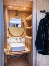 Petite salle d'eau de chalet avec lavabo et miroir rond