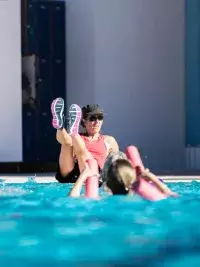 Coach animant un cours d’aquagym en piscine avec participants utilisant des frites en mousse aux Arcs