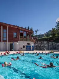 Cours d’aquagym en piscine extérieure avec participants utilisant des frites en mousse aux Arcs