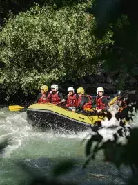 Groupe en rafting franchissant des rapides avec éclaboussures d’eau et végétation autour