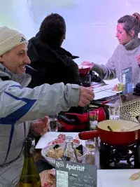 Mensen die samen een fondue eten in een iglo tijdens een gezellig diner in Les Arcs