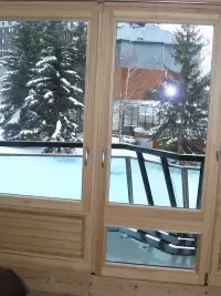 Grande baie vitrée en bois donnant sur un balcon enneigé