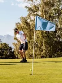 Jeunes golfeurs sur le parcours du golf des Arcs avec les sommets alpins en arrière-plan.