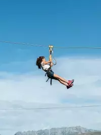 Enfant suspendu à une tyrolienne au-dessus d’un paysage de montagne avec vue dégagée