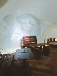 Het interieur van een iglo met houten tafels en banken in een ijsruimte in Les Arcs