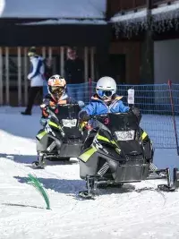 Enfants conduisant des mini-motoneiges sur un parcours enneigé sécurisé aux Arcs