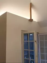 Cloison intérieure beige éclairée sous une poutre en bois