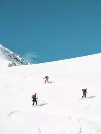 Trois skieurs en randonnée évoluant sur une large pente enneigée avec traces dans la neige aux Arcs