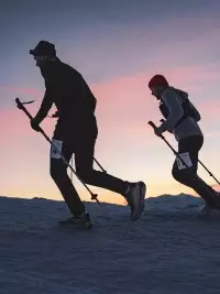Deux participants du Les Arcs Star Trail courant dans la neige au coucher du soleil
