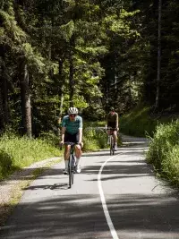 Deux cyclistes sur une route traversant la forêt à Bourg Saint Maurice
