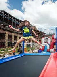 Deux enfants sautent simultanément sur une grande batterie de trampolines extérieurs à Arc 2000, face aux résidences de la station