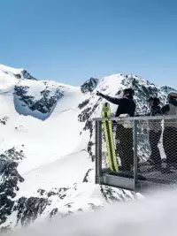 Groupe de skieurs sur une plateforme face aux montagnes alpines.