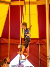 Des enfants s'initient à l'équilibre sur un fil sous un chapiteau de cirque aux Arcs, encadrés par une animatric